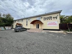 a car parked in a parking lot in front of a building at Damir HOTEL ГОСТИНИЦА in Aktobe