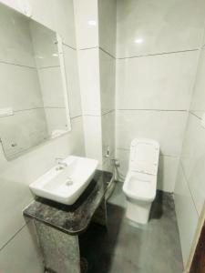 a white bathroom with a sink and a toilet at Hotel Connecting Home Stays in Hingni