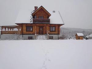 a log house with snow on the ground at Agroturystyka Dzika Łąka apartament 