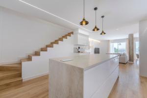 a white kitchen with a counter and stairs at Casa Descubrimiento - Dúplex Moderno con Jardín a 5 minutos de la Playa de Vera in Vera