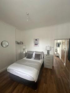 a bedroom with a large white bed and wooden floors at Comfortable cosy one bed flat with garden in se London in Elmers End