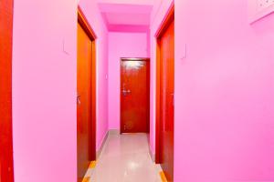 a hallway with pink walls and a red door at Hotel O Lotus Homestay in Bārāsat