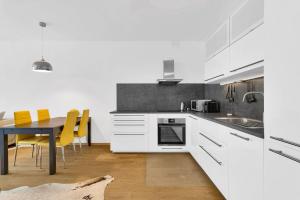 a kitchen with white cabinets and a table with yellow chairs at Riverside luxury apartment in Bratislava