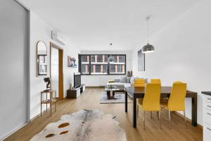 a living room with a dining room table and yellow chairs at Riverside luxury apartment in Bratislava +32 photos