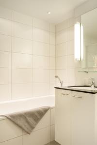 a white bathroom with a tub and a sink at Holzgasse Apartment in Andermatt
