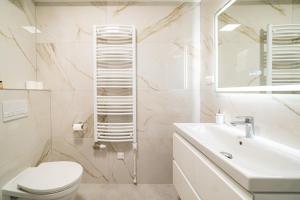 a white bathroom with a toilet and a sink at Hajnal Residence Deluxe with Terrace by Mital in Szeged +51 photos