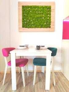 a white table and chairs with a painting on the wall at City Center Sweet Apartment in Niš