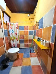a bathroom with a toilet and a tiled floor at Hostel Pantera do Rosa in Praia do Rosa
