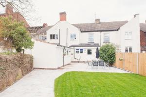 una casa con patio e un cortile con prato verde di LYNNTON HOUSE Stunning 6 bed Town Centre House ALL with En-Suites Prime Location Tamworth a Tamworth