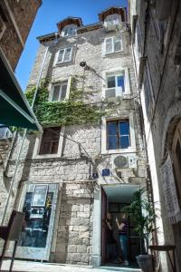 un ancien bâtiment en pierre avec une femme debout à l'entrée dans l'établissement West Wall Apartment, à Split