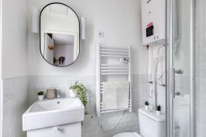 a white bathroom with a sink and a mirror at Suite design Batignolles Lignes 13 & 14 in Paris +15 photos