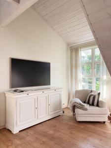 a white living room with a tv and a couch at Stylish Villa - Boat, Greenhouse & Majestic Oaks in Sørvåg +40 photos