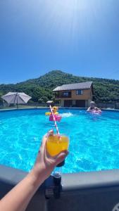 a person holding a drink in front of a swimming pool at Файний будинок in Mizhhirʼʼya