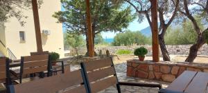 a patio with benches and a stone wall and trees at Domaine Papakonstantis in Skoutari