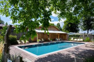 a swimming pool in a yard with a house at Camping Mareveld in Schimmert