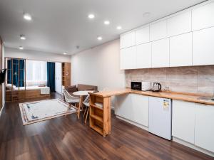 a kitchen with white cabinets and a table and chairs at Апартамент на Тулебаева! in Almaty