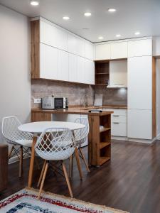 a kitchen with white cabinets and a table and chairs at Апартамент на Тулебаева! in Zhezdi