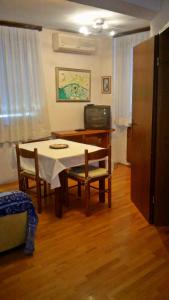 a dining room with a table and chairs and a television at Butul Apartment in Koper