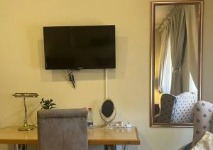Habitación con mesa y TV en la pared. en The Lion Room at Frederick's Place, en Pretoria