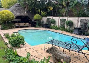 Una pequeña piscina con un banco al lado. en The Lion Room at Frederick's Place, en Pretoria