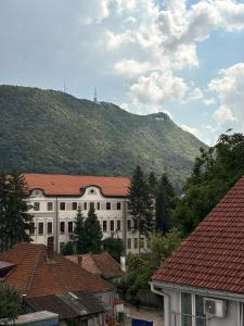 a large white building with a mountain in the background at Hotel City Center in Braşov