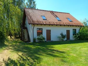 a small white house with a grass yard at Mazurska Apartamenty in Rydzewo
