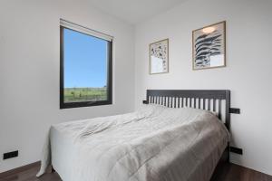 a white bedroom with a bed and a window at Spacious 3BR Summerhouse with Private Hot Tub in Selfoss