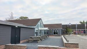 a building with a picnic table and benches next to it at Willows 105 Caravan - 7 Lakes in Crowle
