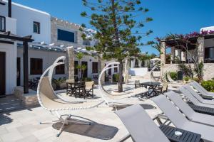 a patio with white chairs and tables and a tree at Contaratos Beach Hotel in Naousa