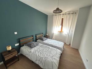 two beds in a bedroom with blue walls at Logement moderne 80m2 - 6 personnes in Folkling