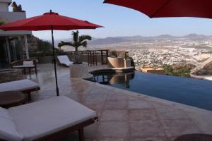 a patio with an umbrella and a swimming pool at Luxury Cabo Villa Stunning Ocean Views in Cabo San Lucas