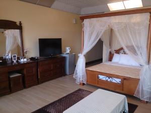 a bedroom with a canopy bed and a television at Sansendai Sea View B&B in Chenggong