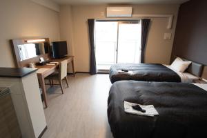 a hotel room with two beds and a desk at Hotel Trad in Osaka