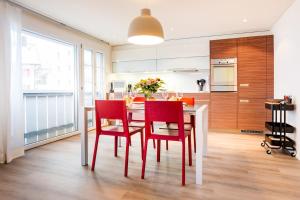 una cucina con tavolo bianco e sedie rosse di Apartment Marmotta a Andermatt Altre 14 foto
