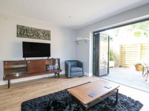 ein Wohnzimmer mit Fernseher, Couch und Tisch in der Unterkunft Sunnyfield Cottage in Coulsdon