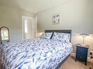 ein Schlafzimmer mit einem Bett mit einer blau-weißen Bettdecke in der Unterkunft Sunnyfield Cottage in Coulsdon