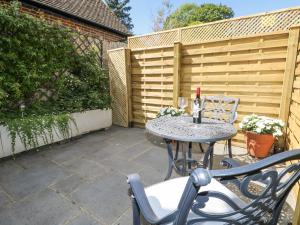 a patio with a table and chairs and a fence at Sunnyfield Cottage in Coulsdon