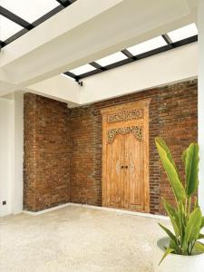 a room with a brick wall with a wooden door at Casa De Cuentos Bali in Denpasar