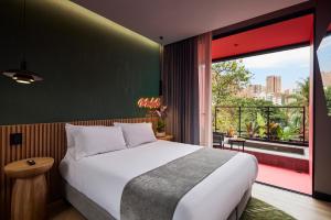 a bedroom with a large bed and a large window at Calle Flora Hotel by Jalo in Medellín