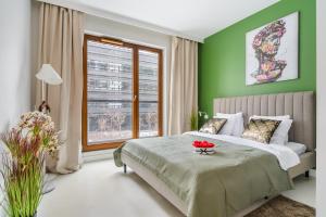 a bedroom with a bed with green walls and a window at Lumina Deluxe Warsaw in Warsaw