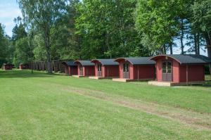 a row of red buildings in a grass field at Karujärve Camping in Paiküla