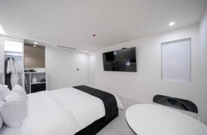 1 dormitorio blanco con 1 cama y TV en la pared en aiden, en Busan