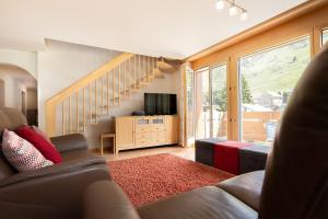 a living room with a couch and a staircase at Annika Apartment in Andermatt