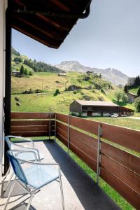 a pair of chairs sitting on a porch with a fence at Annika Apartment in Andermatt