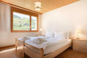a bedroom with a large white bed with a window at Annika Apartment in Andermatt