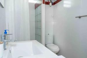 a white bathroom with a toilet and a sink at Maison chaleureuse aux Abymes avec jacuzzi relaxant in Les Abymes +35 photos