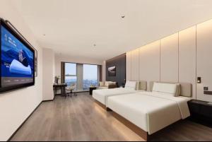 Atour Hotel Suzhou Jinji Lake East Park High-Speed Rail Station في سوتشو: غرفة نوم بها سرير أبيض كبير وتلفزيون بشاشة مسطحة