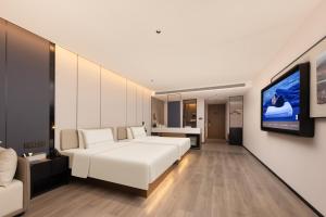 Atour Hotel Suzhou Jinji Lake East Park High-Speed Rail Station في سوتشو: غرفة نوم بسرير ابيض وتلفزيون بشاشة مسطحة