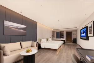 Atour Hotel Suzhou Jinji Lake East Park High-Speed Rail Station في سوتشو: غرفة معيشة مع أريكة بيضاء وسرير