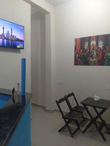 a room with two chairs and a table and a tv at Suites Aparecida in Aparecida